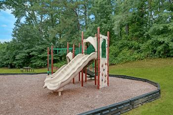 A playground with a slide and a green fence.